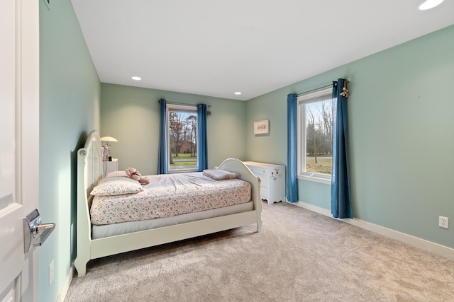 bedroom with multiple windows and light carpet