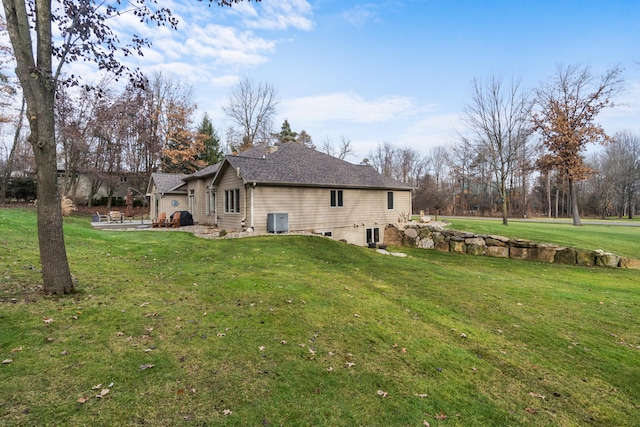 back of house with cooling unit and a lawn