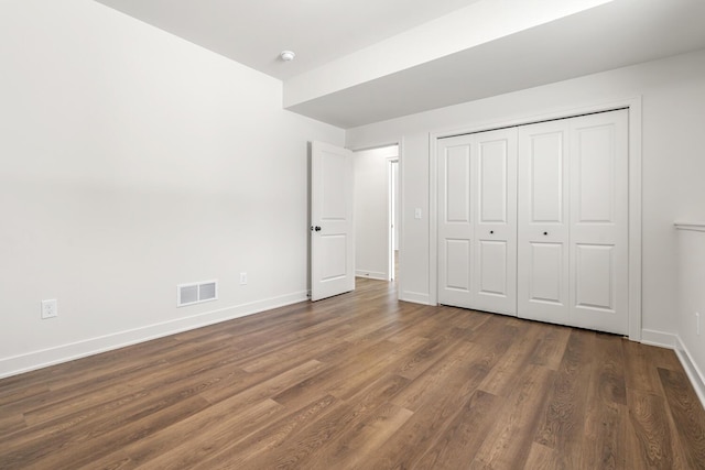 unfurnished bedroom with dark wood-type flooring and a closet