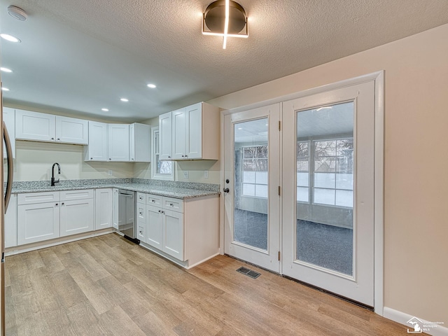 kitchen featuring a textured ceiling, dishwasher, light hardwood / wood-style floors, and white cabinets