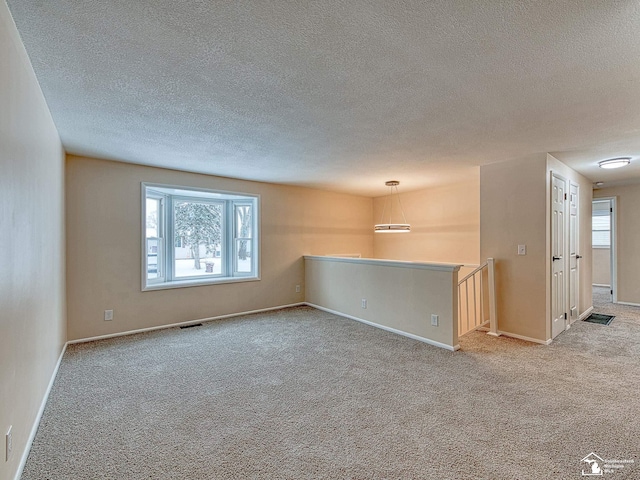 carpeted spare room with a textured ceiling