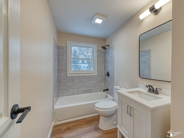 full bathroom featuring vanity, hardwood / wood-style floors, tiled shower / bath, and toilet