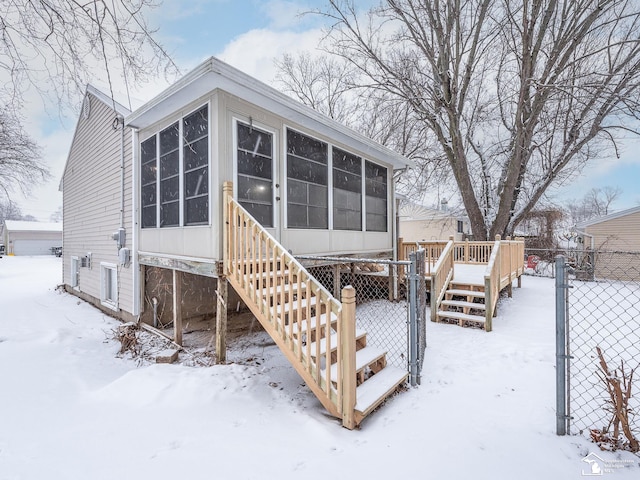 snow covered property featuring a wooden deck and a sunroom