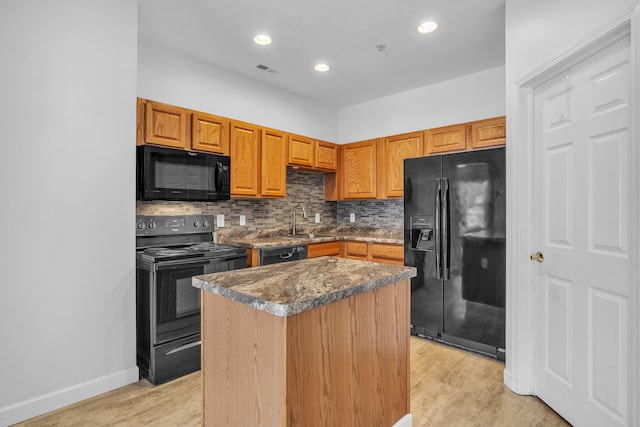 kitchen featuring a center island, sink, light hardwood / wood-style floors, and black appliances