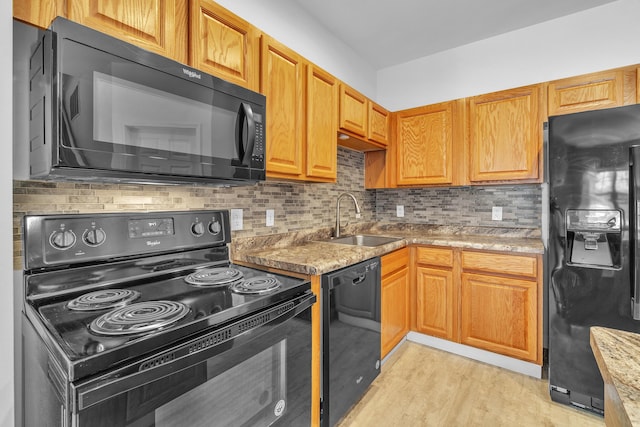 kitchen featuring sink, backsplash, black appliances, light stone countertops, and light wood-type flooring