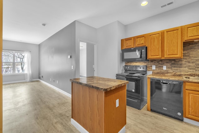 kitchen featuring tasteful backsplash, sink, light hardwood / wood-style floors, and black appliances