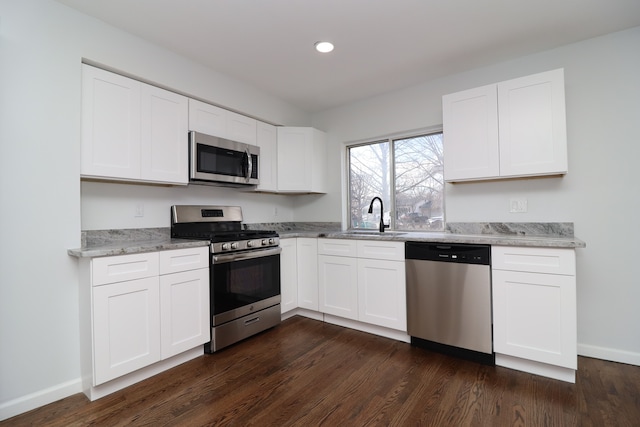 kitchen with sink, white cabinetry, stainless steel appliances, light stone countertops, and dark hardwood / wood-style flooring