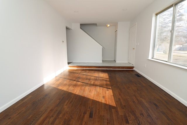 empty room with dark hardwood / wood-style flooring and a healthy amount of sunlight