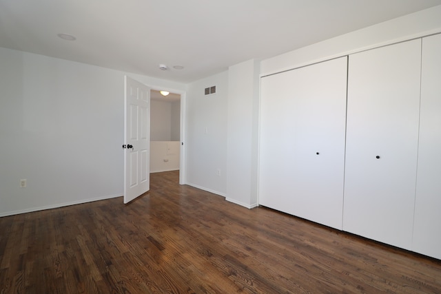 unfurnished bedroom featuring dark hardwood / wood-style flooring and a closet