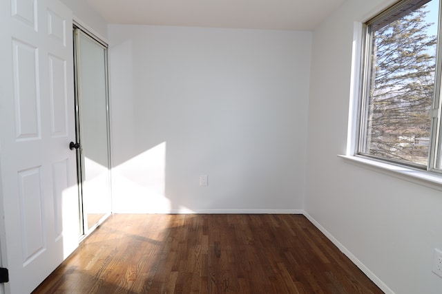 unfurnished bedroom with dark wood-type flooring, a closet, and multiple windows