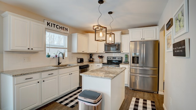 kitchen featuring a kitchen island, pendant lighting, sink, white cabinets, and stainless steel appliances