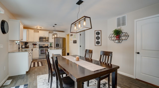 dining area featuring dark wood-style floors, visible vents, and baseboards