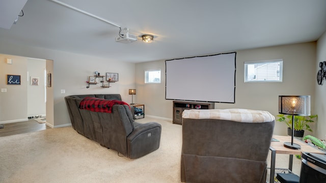 home theater room featuring a healthy amount of sunlight, light colored carpet, and baseboards