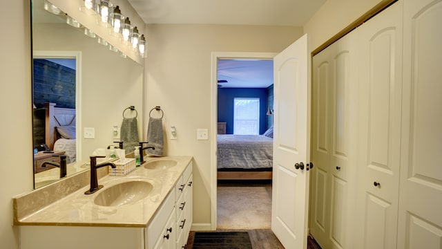 ensuite bathroom featuring double vanity, connected bathroom, and a sink