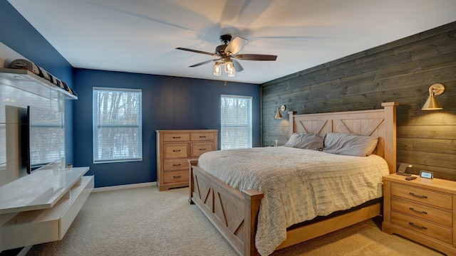 carpeted bedroom featuring multiple windows, ceiling fan, and wood walls