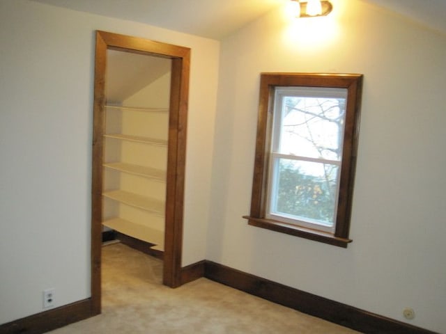 corridor with lofted ceiling and light colored carpet