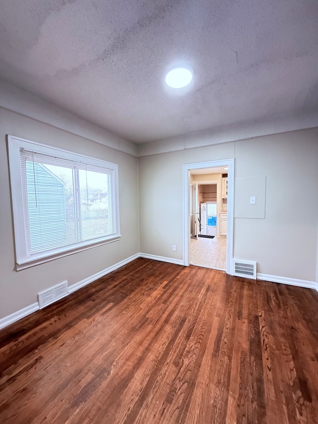 unfurnished room with dark hardwood / wood-style floors and a textured ceiling