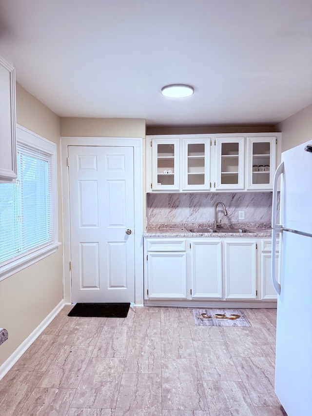 kitchen with sink, light stone countertops, white cabinets, and white fridge