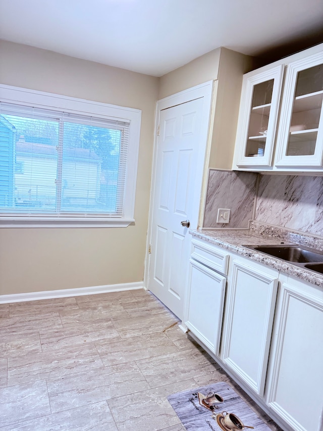 kitchen with white cabinetry, light stone countertops, and decorative backsplash