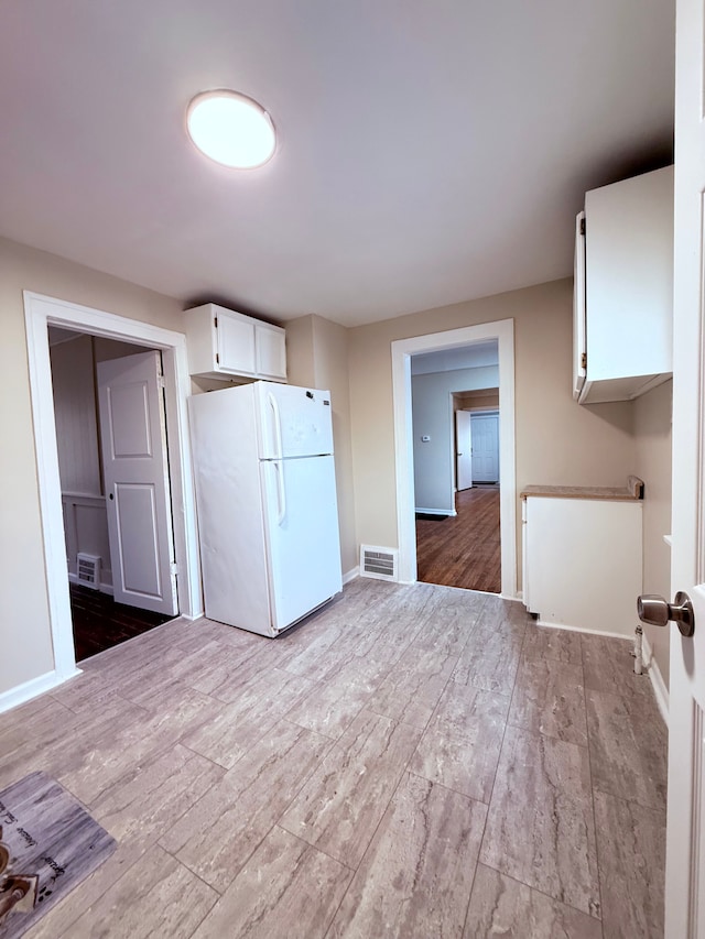 kitchen featuring light wood-type flooring, white cabinets, and white refrigerator