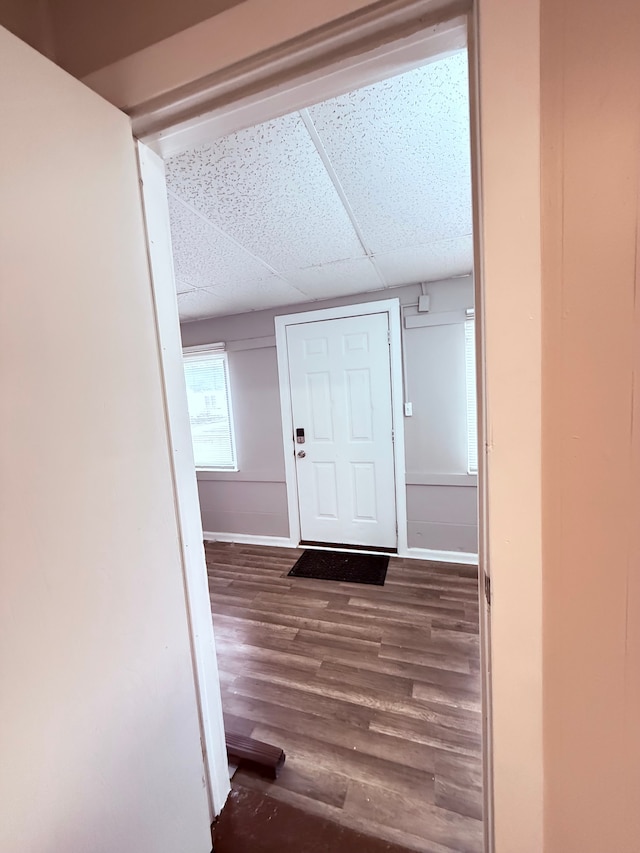 corridor with dark hardwood / wood-style flooring and a paneled ceiling