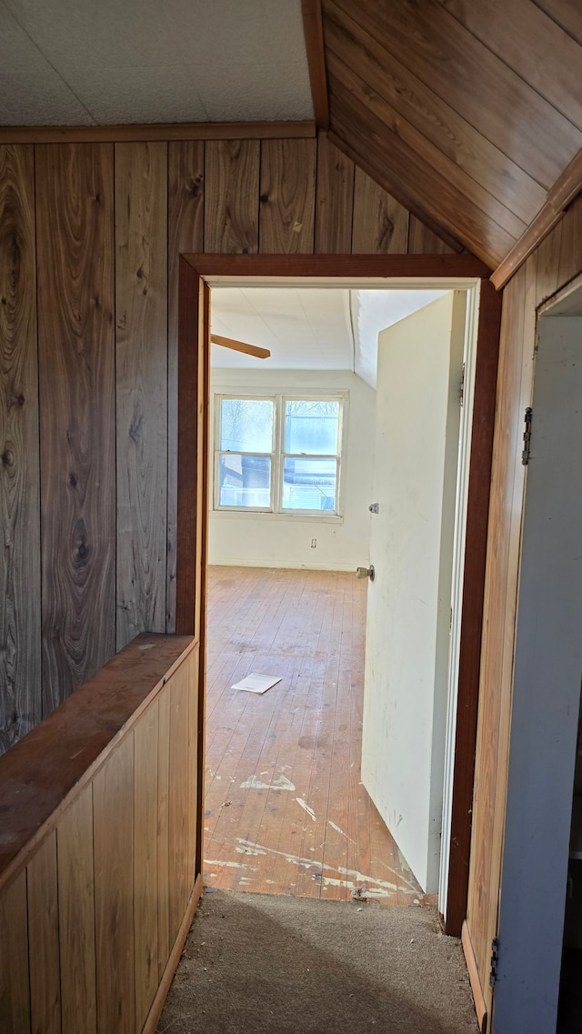 corridor featuring wooden walls and vaulted ceiling