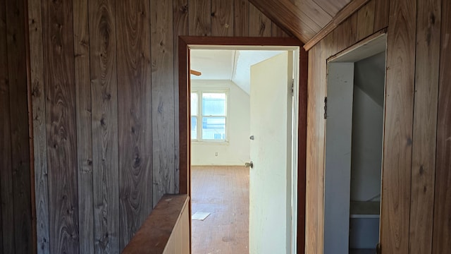 hallway with lofted ceiling and wood walls