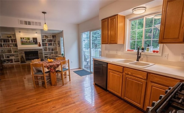 kitchen featuring gas stove, sink, light hardwood / wood-style flooring, dishwasher, and pendant lighting