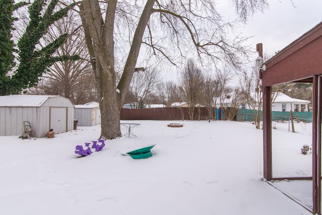 snowy yard featuring a shed