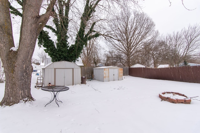 yard covered in snow featuring a storage unit and a fire pit