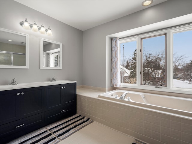 bathroom with a relaxing tiled tub, vanity, and tile patterned flooring