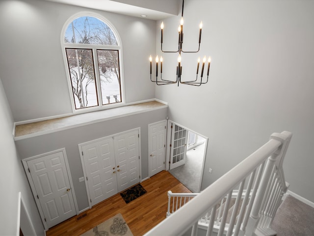 foyer featuring wood-type flooring, a chandelier, and a high ceiling