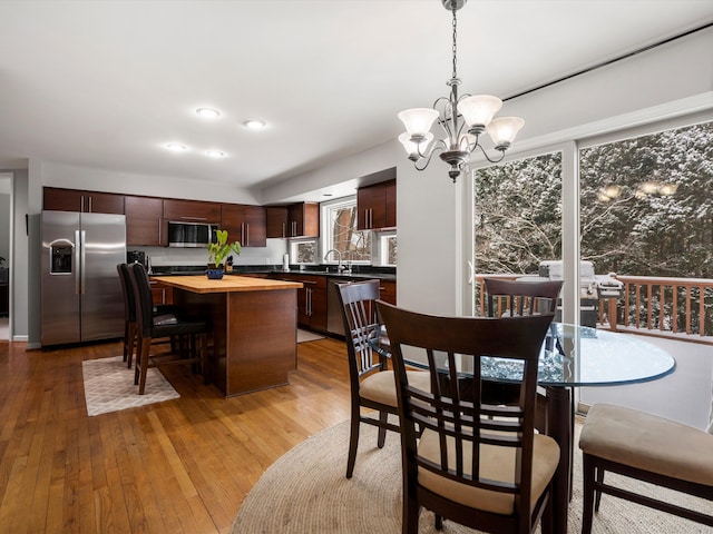 dining space with sink, an inviting chandelier, and light hardwood / wood-style floors