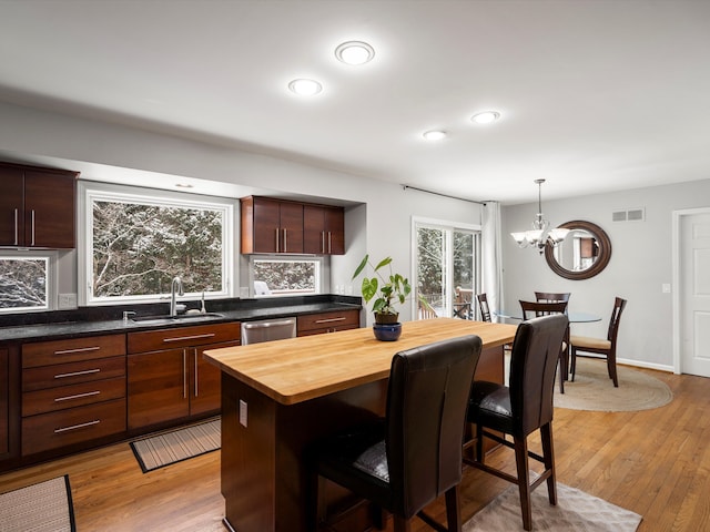 kitchen with a breakfast bar, tasteful backsplash, sink, a chandelier, and stainless steel dishwasher