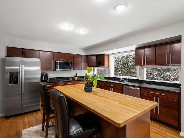 kitchen with stainless steel appliances, a center island, sink, and wood counters