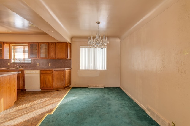 kitchen featuring pendant lighting, white dishwasher, tasteful backsplash, carpet floors, and a chandelier