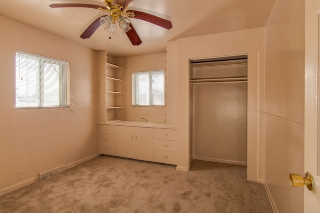 unfurnished bedroom featuring multiple windows, ceiling fan, a closet, and light carpet