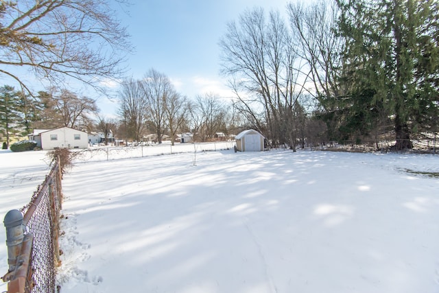 yard layered in snow featuring a storage unit