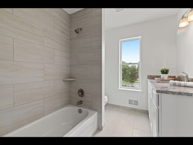 full bathroom featuring tiled shower / bath, vanity, toilet, and tile patterned flooring