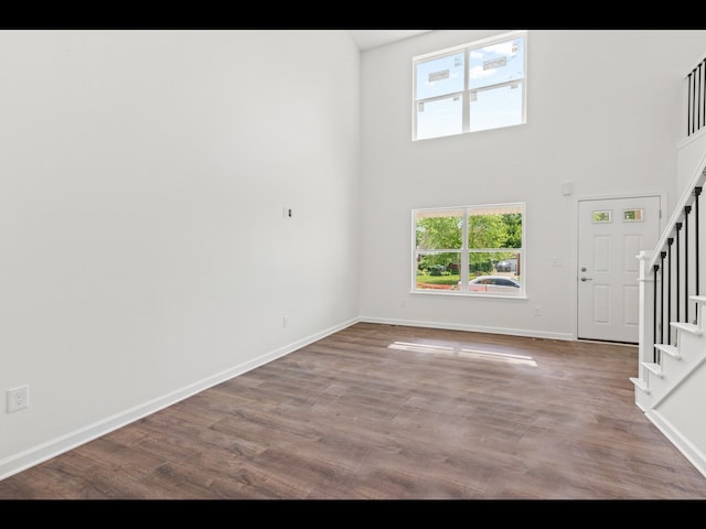 unfurnished living room featuring hardwood / wood-style flooring and a towering ceiling