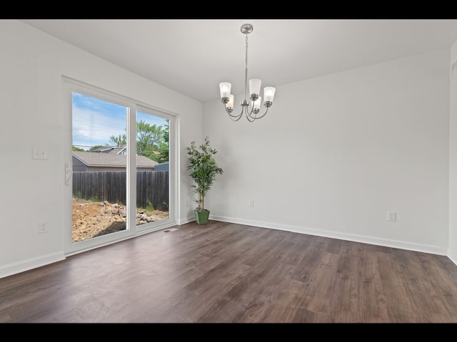 spare room with dark hardwood / wood-style floors and a notable chandelier