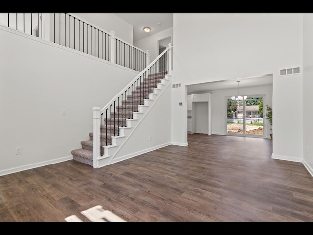 interior space with a high ceiling, hardwood / wood-style floors, and an inviting chandelier