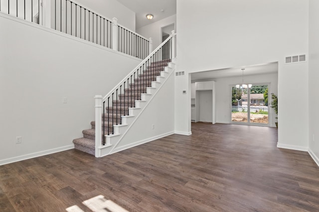 interior space with dark wood-type flooring, a high ceiling, and a notable chandelier