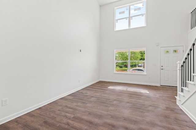 unfurnished living room featuring hardwood / wood-style flooring and a towering ceiling