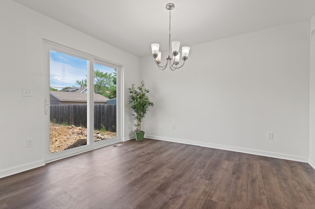 empty room with dark hardwood / wood-style flooring and a notable chandelier