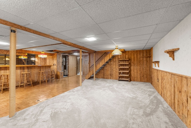 basement featuring parquet floors, wood walls, and indoor bar