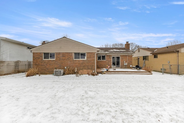 snow covered back of property featuring central AC and a deck