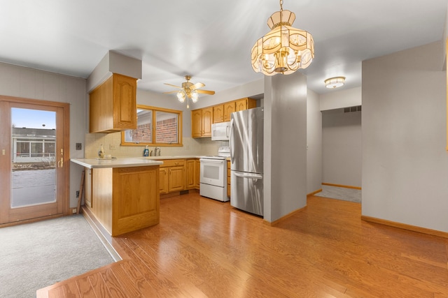 kitchen with light brown cabinetry, sink, tasteful backsplash, hanging light fixtures, and white appliances