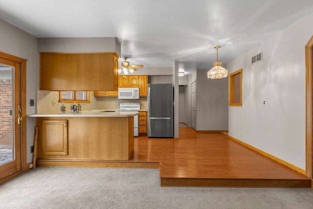 kitchen with light carpet, white appliances, decorative light fixtures, and kitchen peninsula