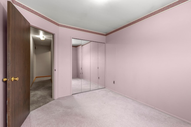 unfurnished bedroom with light colored carpet and a closet